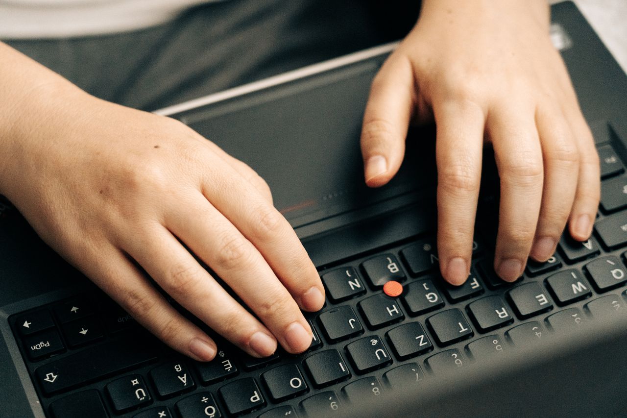 Close-up of hands typing on a black laptops keyboard emphasizing productivity.
